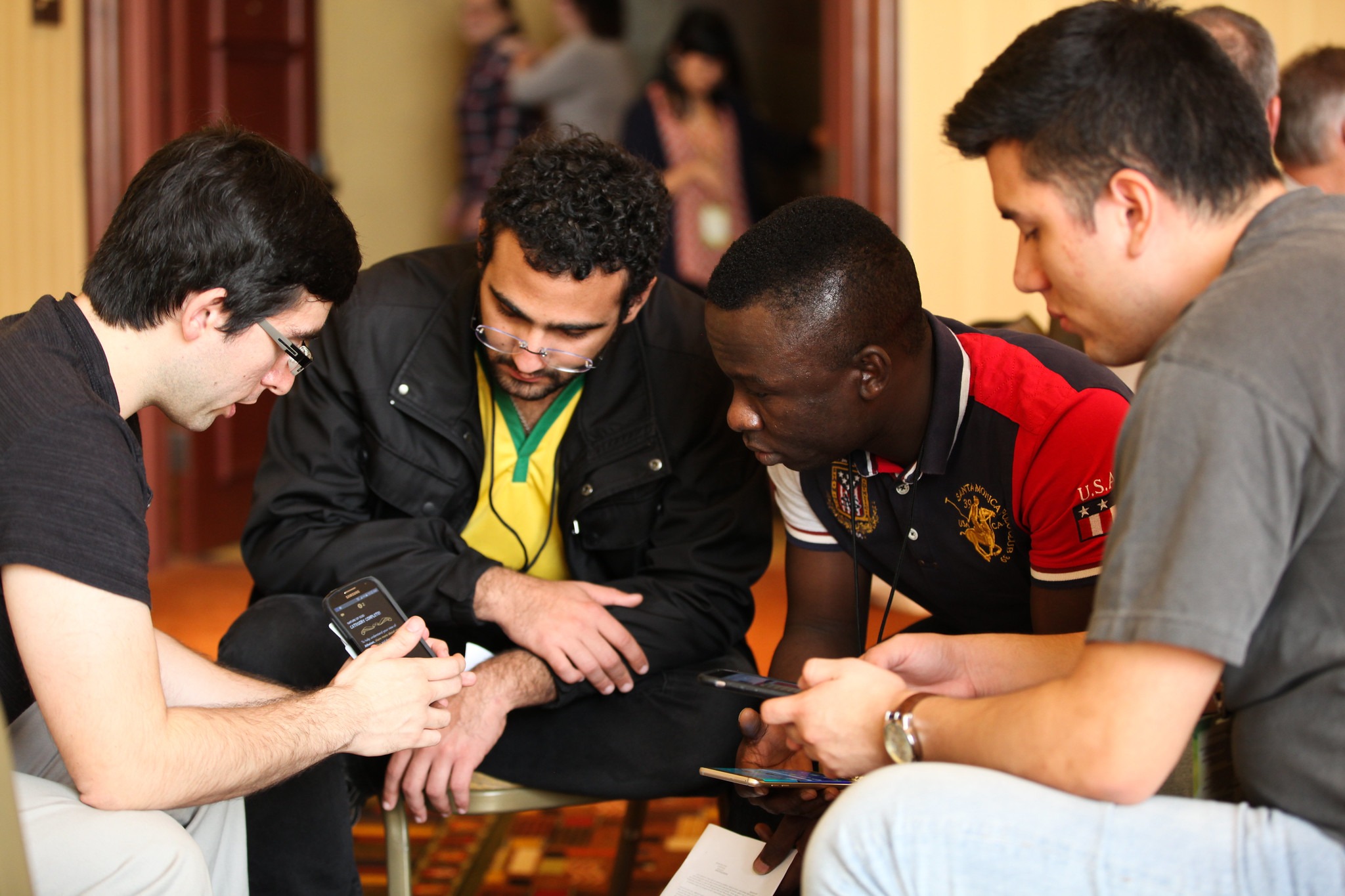 four diverse young men look at gospel tract on a phone